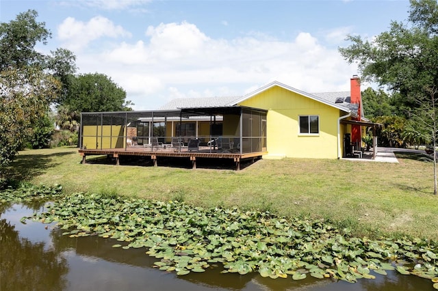 back of house with a yard, a chimney, a water view, and a sunroom