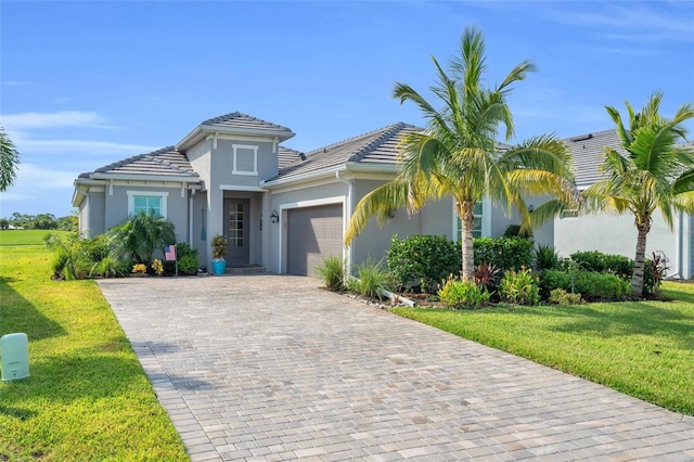 mediterranean / spanish-style home featuring decorative driveway, stucco siding, an attached garage, a front yard, and a tiled roof