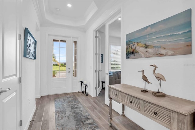 interior space with crown molding, a tray ceiling, and light hardwood / wood-style floors