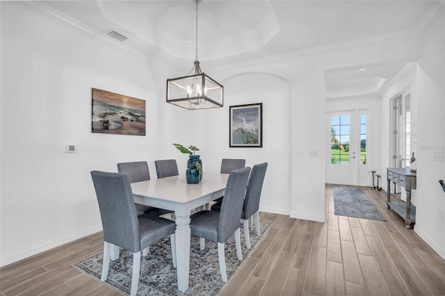 dining area with a tray ceiling, ornamental molding, hardwood / wood-style flooring, and a chandelier