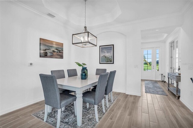 dining room featuring visible vents, baseboards, ornamental molding, wood tiled floor, and a raised ceiling