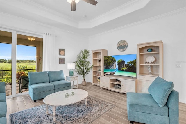 living room featuring ornamental molding, a tray ceiling, a ceiling fan, and wood tiled floor