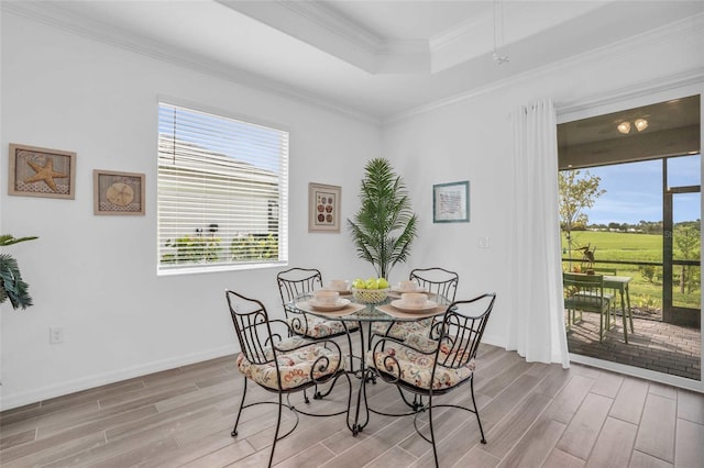 dining space with wood tiled floor, baseboards, a raised ceiling, and crown molding