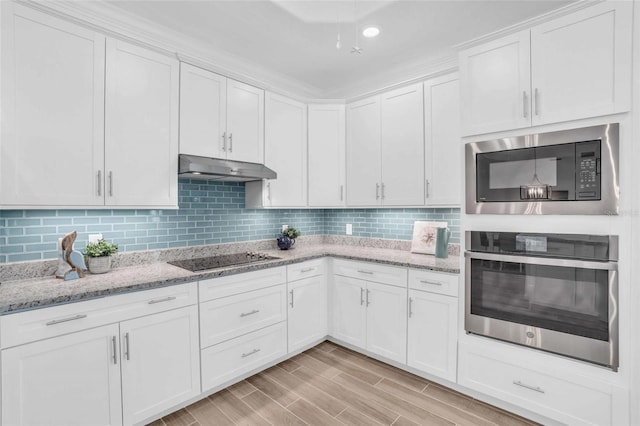 kitchen featuring black electric cooktop, under cabinet range hood, stainless steel oven, backsplash, and built in microwave