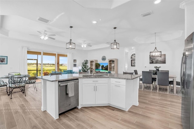 kitchen featuring wood finish floors, a sink, visible vents, open floor plan, and appliances with stainless steel finishes