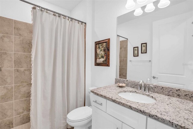 bathroom featuring a tile shower, vanity, and toilet