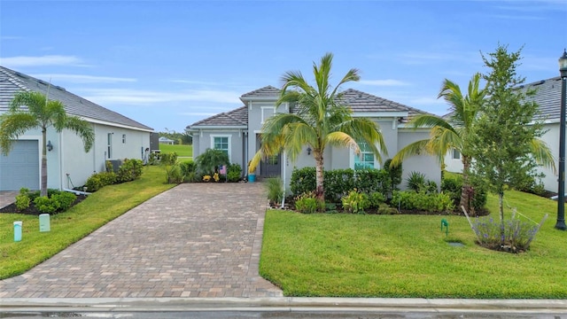 mediterranean / spanish-style house featuring a front lawn, decorative driveway, and stucco siding