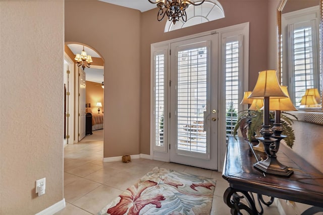 tiled foyer featuring plenty of natural light and a chandelier