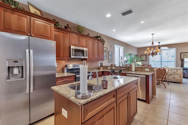 kitchen featuring a kitchen island with sink, appliances with stainless steel finishes, an inviting chandelier, and hanging light fixtures