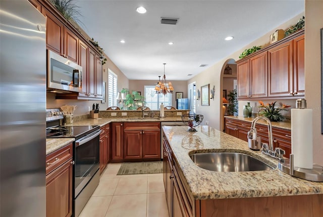 kitchen with an inviting chandelier, decorative light fixtures, appliances with stainless steel finishes, light stone countertops, and sink