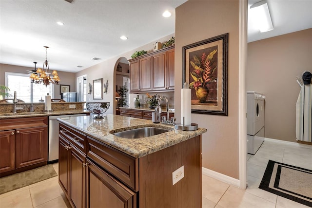 kitchen with a kitchen island with sink, pendant lighting, a chandelier, and sink