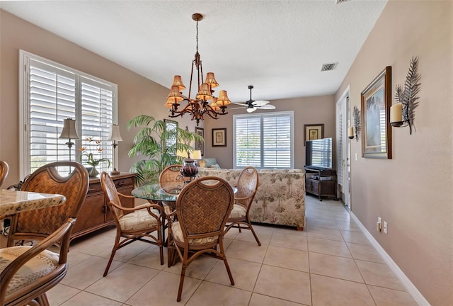 dining space with light tile patterned floors, ceiling fan with notable chandelier, and a textured ceiling