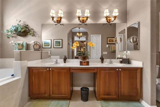 bathroom with toilet, tile patterned floors, vanity, a chandelier, and a relaxing tiled tub