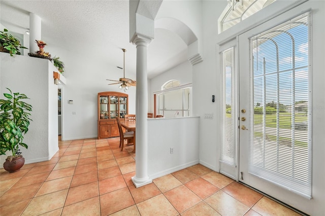 foyer featuring ornate columns, ceiling fan, light tile patterned floors, and a healthy amount of sunlight