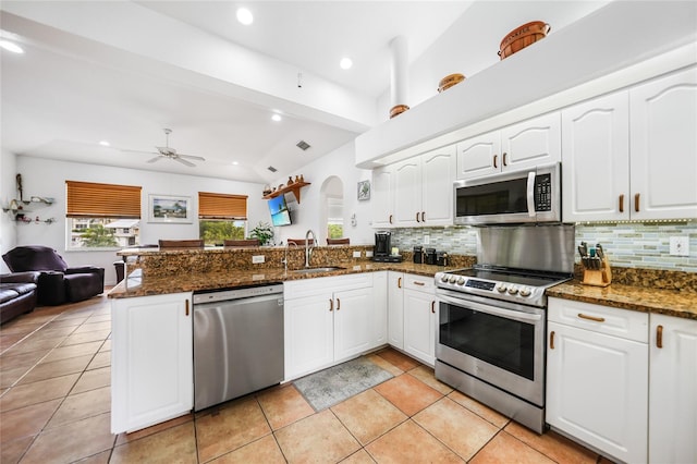 kitchen featuring appliances with stainless steel finishes, kitchen peninsula, sink, ceiling fan, and dark stone counters