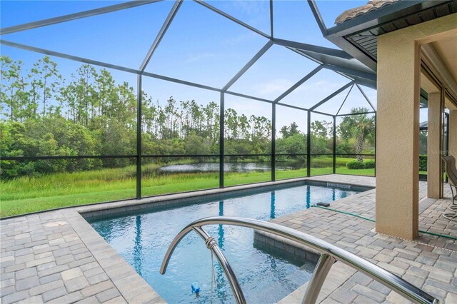 view of pool with glass enclosure, a water view, and a patio