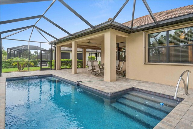 view of pool with glass enclosure, a patio area, and ceiling fan