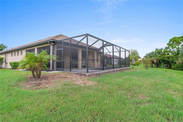 rear view of house with a tile roof, glass enclosure, a patio area, and a lawn