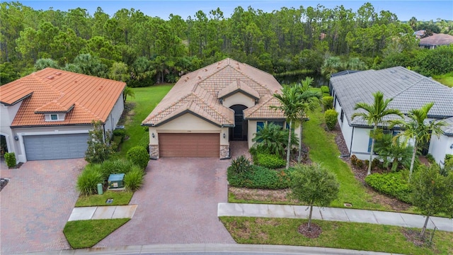 view of front facade with a garage, decorative driveway, a tile roof, and stucco siding