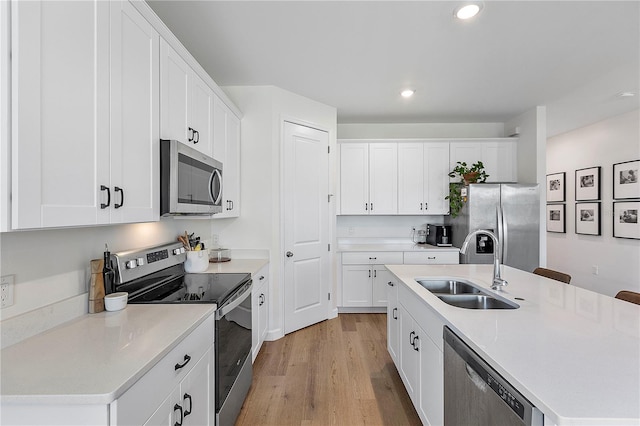 kitchen featuring light hardwood / wood-style flooring, a kitchen island with sink, stainless steel appliances, sink, and white cabinets