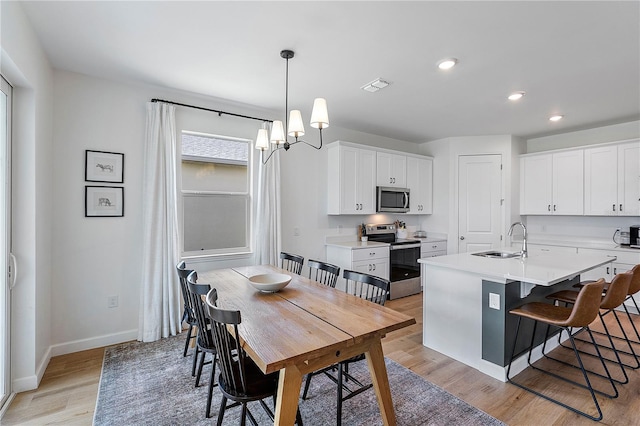 dining area featuring light hardwood / wood-style flooring, sink, and a chandelier