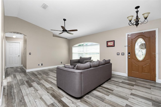 living room with vaulted ceiling, ceiling fan with notable chandelier, and light wood-type flooring