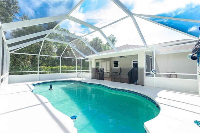 view of pool with glass enclosure, ceiling fan, and a patio area