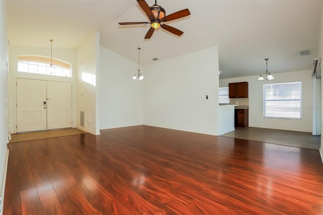 unfurnished living room with ceiling fan with notable chandelier, lofted ceiling, a wealth of natural light, and wood-type flooring