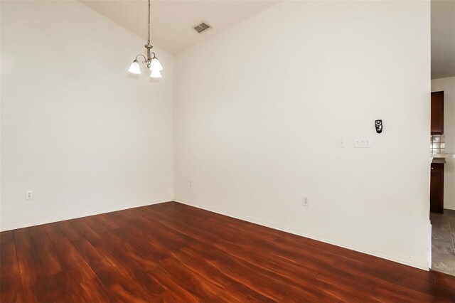 unfurnished room with lofted ceiling, wood-type flooring, and an inviting chandelier