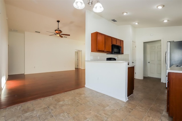 kitchen featuring vaulted ceiling, ceiling fan with notable chandelier, light hardwood / wood-style flooring, backsplash, and hanging light fixtures