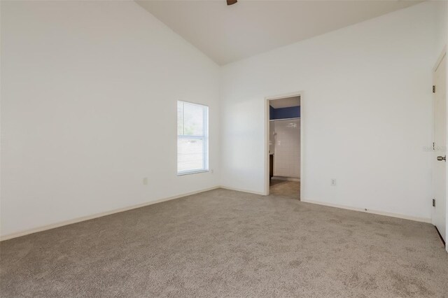 empty room featuring light carpet and high vaulted ceiling