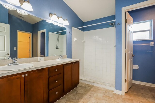 bathroom with vanity, lofted ceiling, and tiled shower