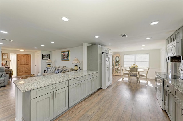 kitchen featuring gray cabinetry, light stone counters, white appliances, and light wood-type flooring