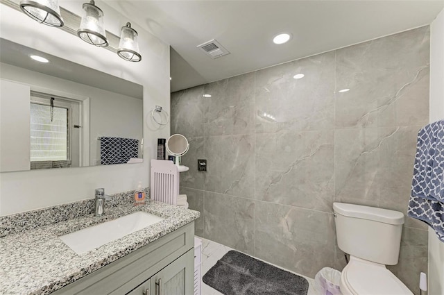 bathroom with vanity, tile walls, and toilet