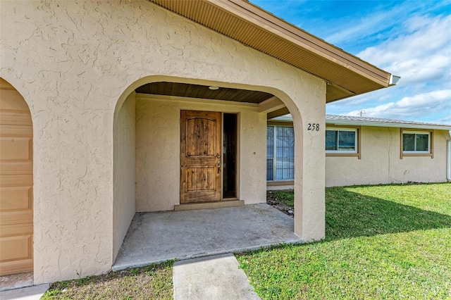 entrance to property featuring a yard and a garage