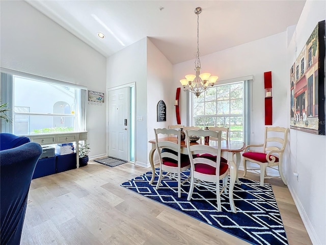 dining area with vaulted ceiling, hardwood / wood-style floors, and an inviting chandelier