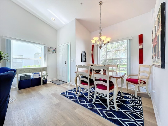 dining area with high vaulted ceiling, wood-type flooring, and a chandelier