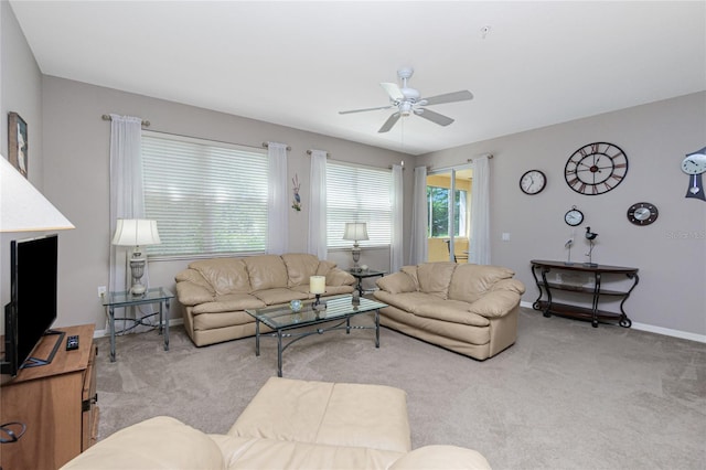 living area with ceiling fan, baseboards, and light colored carpet