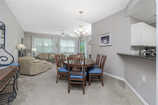 carpeted dining room featuring ceiling fan with notable chandelier