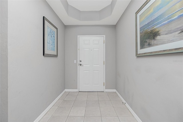 doorway to outside with a raised ceiling and light tile patterned flooring