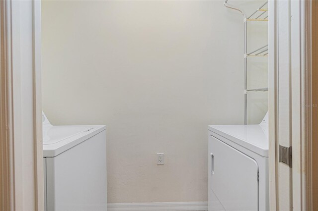 laundry room with laundry area, baseboards, and washer and clothes dryer