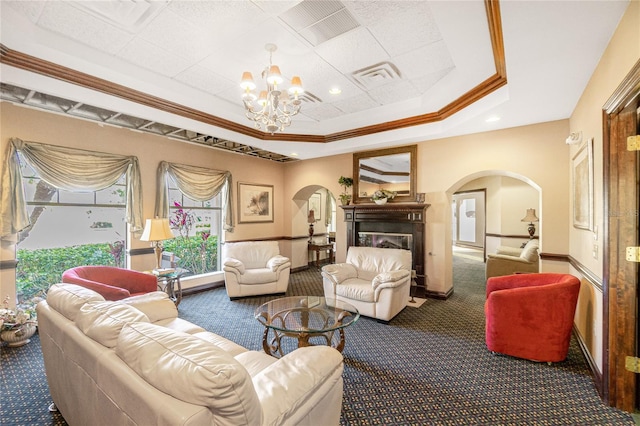 carpeted living area featuring arched walkways, a tray ceiling, a glass covered fireplace, and visible vents