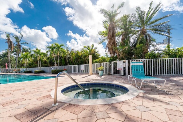 community pool featuring a community hot tub, a patio area, and fence