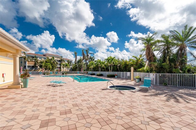 pool with a community hot tub, a patio, and fence