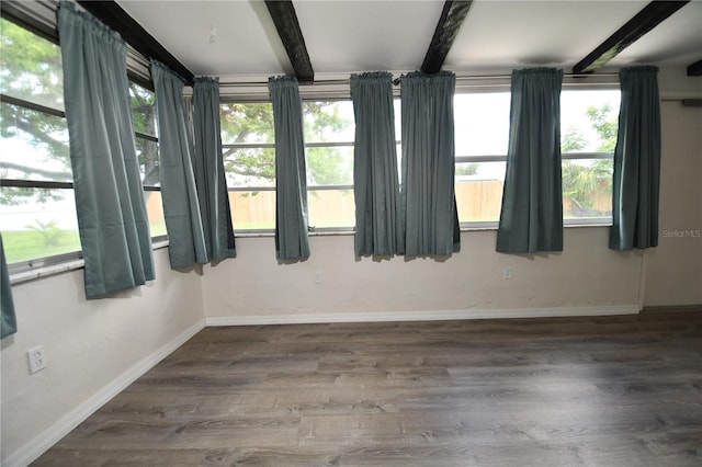 empty room with hardwood / wood-style flooring and beamed ceiling