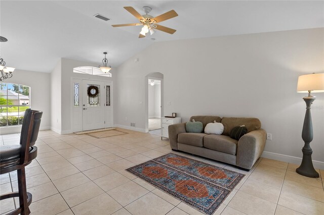 tiled living room featuring ceiling fan with notable chandelier and lofted ceiling