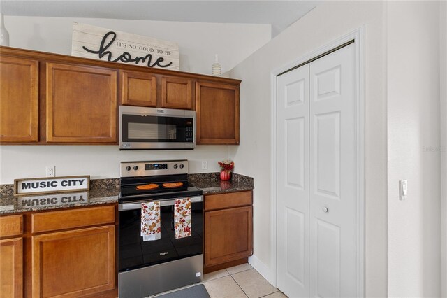 kitchen with dark stone countertops, light tile patterned floors, and stainless steel appliances