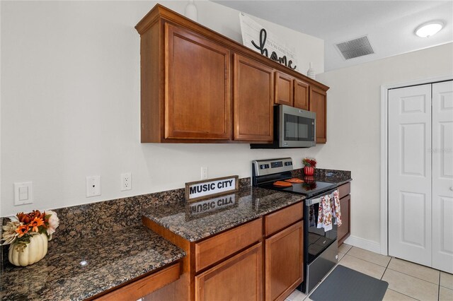 kitchen featuring dark stone counters, light tile patterned floors, and stainless steel appliances