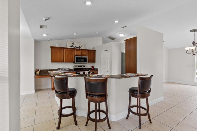 kitchen with dark stone countertops, hanging light fixtures, appliances with stainless steel finishes, a chandelier, and lofted ceiling