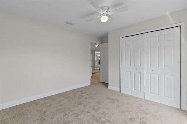 unfurnished bedroom featuring light colored carpet, ceiling fan, and a closet